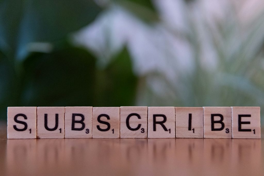 Wooden blocks spelling subscribe on a table, illustrating a custom subscription workflow in WooCommerce