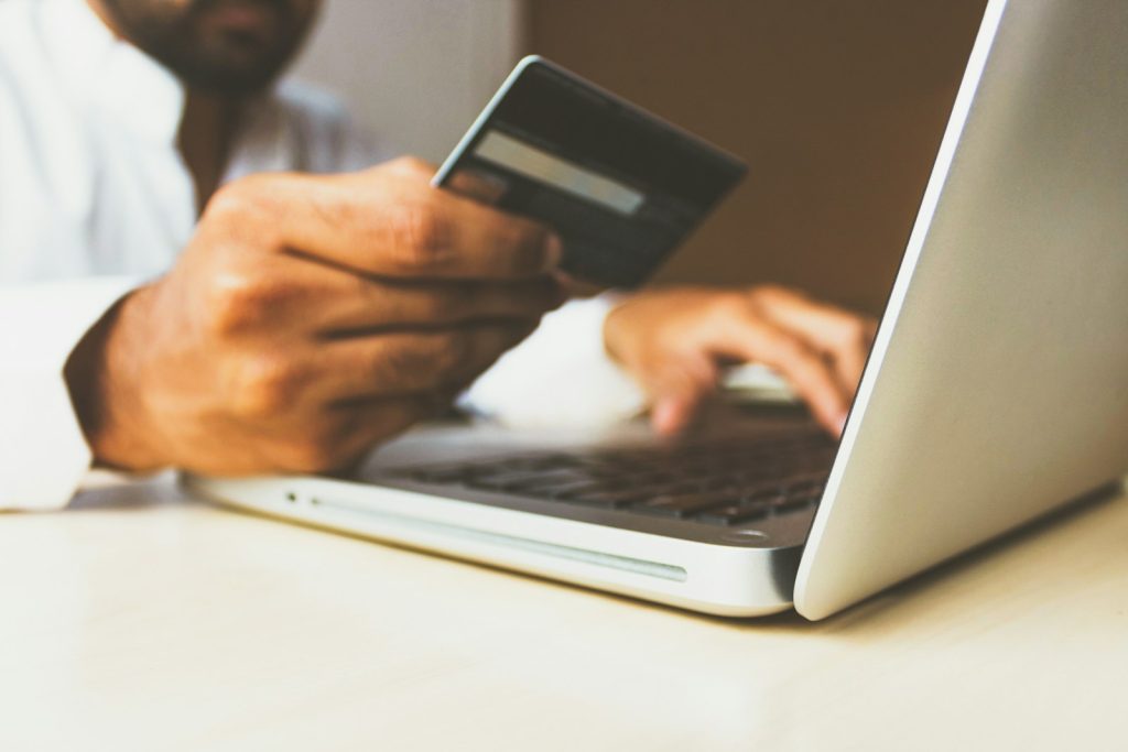 Person holding a bank card while checking out on a laptop, illustrating a slow WooCommerce checkout page